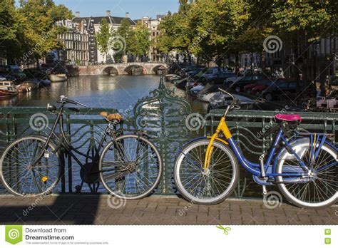 Two Bikes In Autumn Day In Amsterdam With Buildings And Bridge