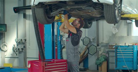 Car Mechanic Is Working Under A Vehicle On A Lift In Service Repairman