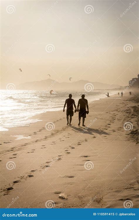 Silhouette Of Two Friends Walking On The Beach During Sunset Editorial
