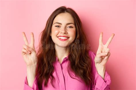 Close Up Of Positive Brunette Female Model Showing Peace Signs Smiling And Having Fun Good