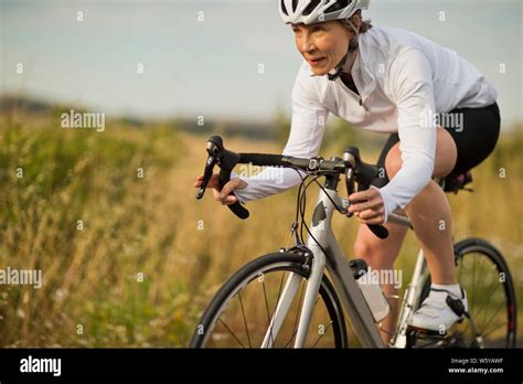 Happy Mature Woman Cycling Along A Country Road Stock Photo Alamy
