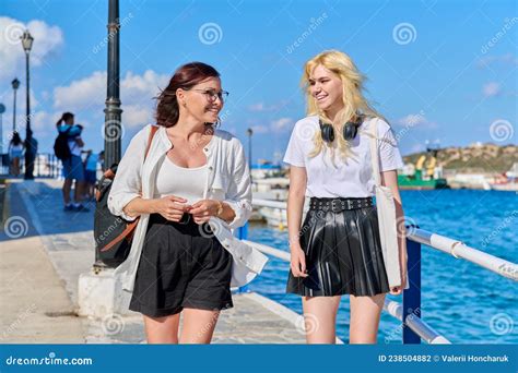 Mom And Teenage Daughter Walking Talking Together In Summer City Stock