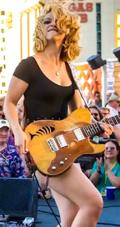 A Woman Is Playing An Electric Guitar In Front Of A Crowd At A Music