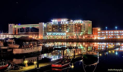 Boats Are Docked In The Water At Night Near Some Buildings And Lights