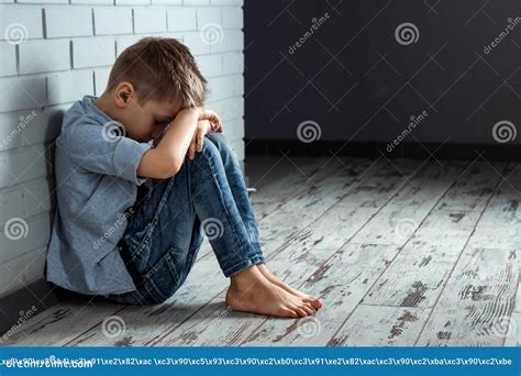 A Young Boy Sits Alone With A Sad Feeling At School Near The Wall