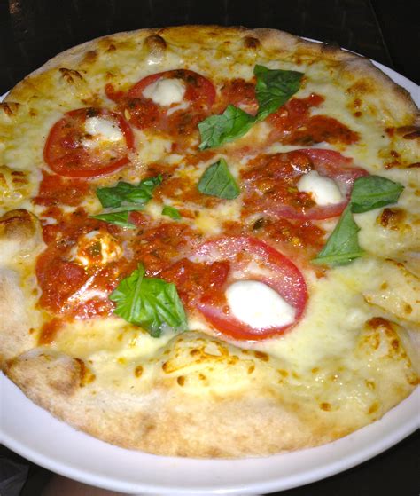 A Pizza With Tomatoes Basil And Mozzarella Cheese On It Sitting On A