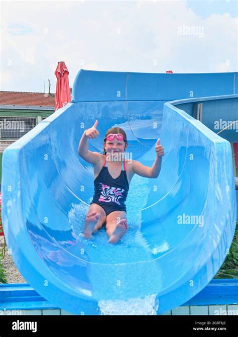 Girl Sliding Down On A Water Slide Into Plunge Pool In Aqua Park Vacation Concept Holiday Fun