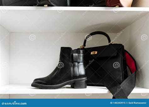 Pair Of Black Leather Shoes With Low Heels And A Black Bag With A Gold