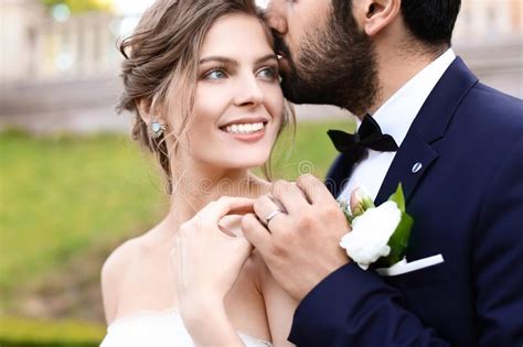 Handsome Young Groom Kissing His Happy Bride Outdoors Stock Photo