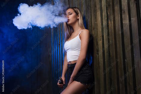foto stock cloud of smoke sexy girl vapeing and smoking electronic cigarette smoking vape mod