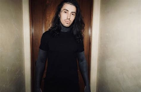 A Man With Long Hair And Black Shirt Standing In Front Of An Open