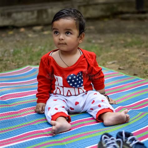 Cute Little Indian Infant Sitting Enjoying Outdoor Shoot At Society