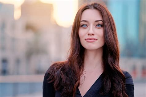 Close Up Portrait Of Beautiful Caucasian Woman With Charming Smile And Long Hair On The City