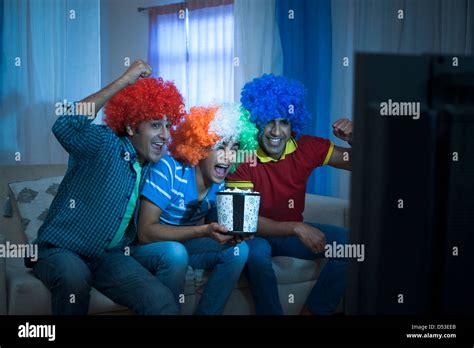 Friends Looking Excited While Watching Cricket Match On The Television