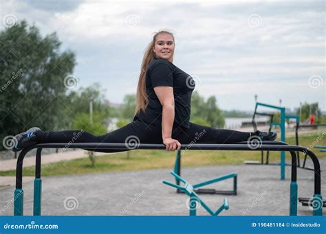 A Beautiful Smiling Overweight Young Woman Stretches For Split On