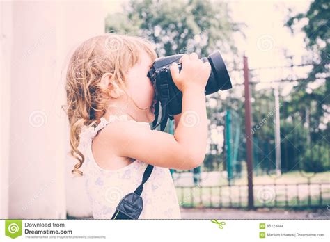 Little Girl Holding A Camera And Taking Pictures Stock Photo Image