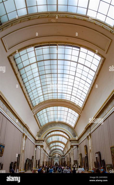 Vertical Shot Of The Corridor Full Of Visitors At The Louvre Museum