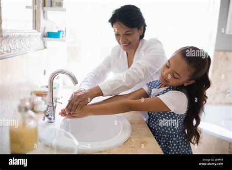 Grandmother And Granddaughter Washing Hands At Bathroom Sink Stock