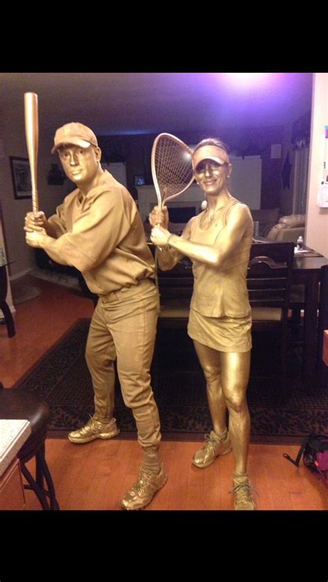 Two Bronze Statues Of People Holding Tennis Rackets