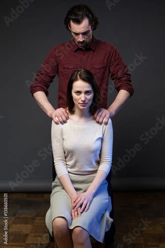 Young Couple Woman Is Sitting On The Chair The Man Is Standing Behind His Hands Keeping Her