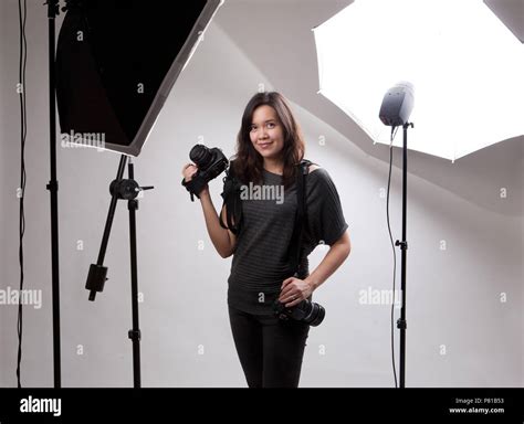 Female Photographer Posing With Her Cameras In The Studio Stock Photo