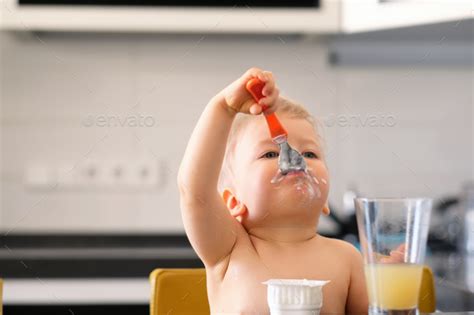 Adorable One Year Old Baby Boy Eating Yoghurt With Spoon Stock Photo By