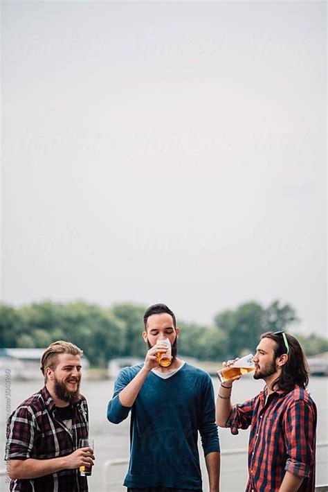 Three Men Standing Next To Each Other Drinking Beer