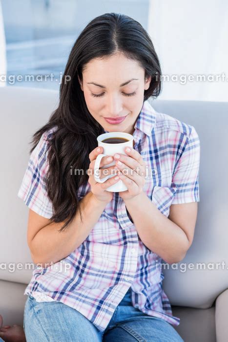 Pretty Brunette Holding Coffee Mug On Couch