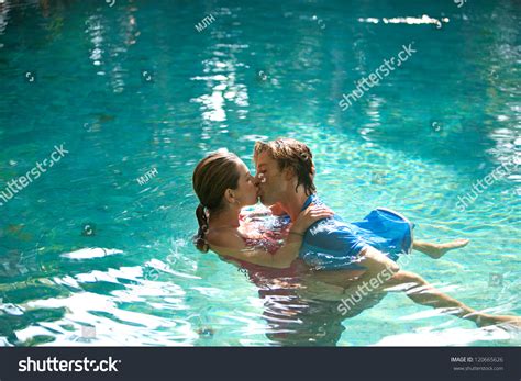 Sexy Young Couple Submerged In A Swimming Pool While Dressed Hugging