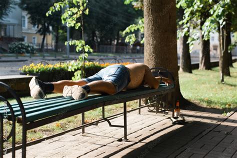 Unrecognizable Drunk Half Naked Man Sleeping On Park Bench On Sunny
