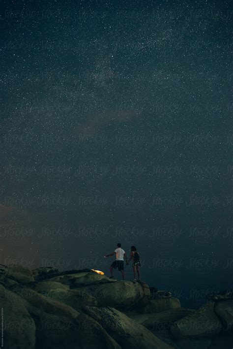 Couple Exploring The Rocky Beach Under The Night Sky Del Colaborador