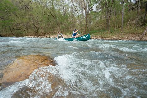Two People In Canoes Paddling Down A River