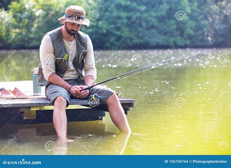 Mature Man Fishing In Lake While Sitting On Pier Stock Photo Image Of