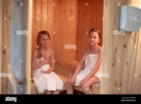 Dos Niñas Han Envuelto En Toallas Y Están Sentados En Una Sauna Finlandesa Fotografía De Stock