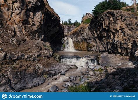Beautiful Shot Of A Waterfall Cascades Down A Rocky Hill On A Sunny Day