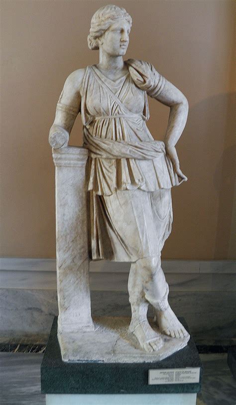 A Statue Of A Woman Holding A Vase In Her Right Hand And Standing On A