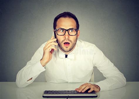Shocked Businessman Talking On Phone While Using Computer Stock Image