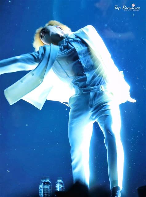 A Male In A White Shirt And Blue Pants On Stage With His Arms Out To