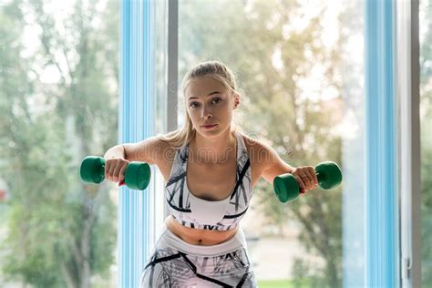 Pretty Blonde Girl Doing Exercise With Light Dumbbells In The Fitness