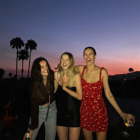 Three Women Standing Next To Each Other In Front Of Palm Trees At Night