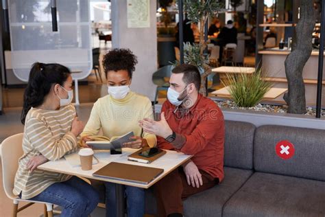 Group Of People Wearing Masks During Meeting In Cafe Stock Photo