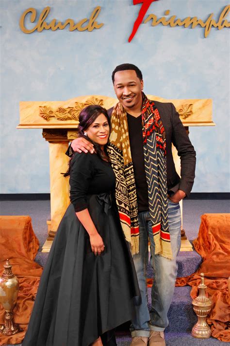 a man and woman standing next to each other in front of a sign that