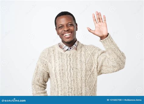Young African American Man Dressed In Sweatersaying Hi Waving His Hand