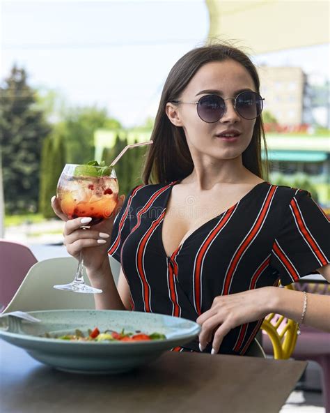 Young Woman Eating Salad With Strawberries And Drinking Aperol Spritz Cocktail In Outdoor