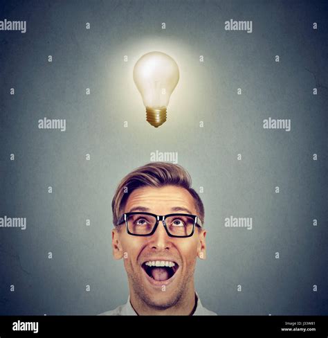 Happy Man In Glasses Looking Up At Bright Light Idea Bulb Above Head
