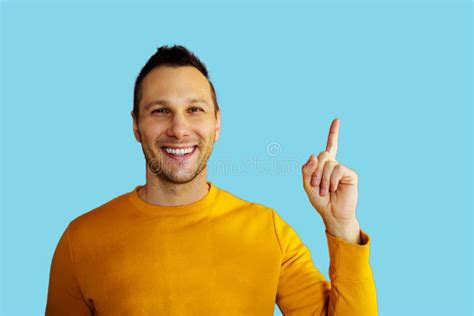 Attractive Young Man In Yellow T Shirt Pointing Up With His Finger