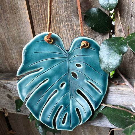 a blue ceramic leaf hanging on a wooden fence