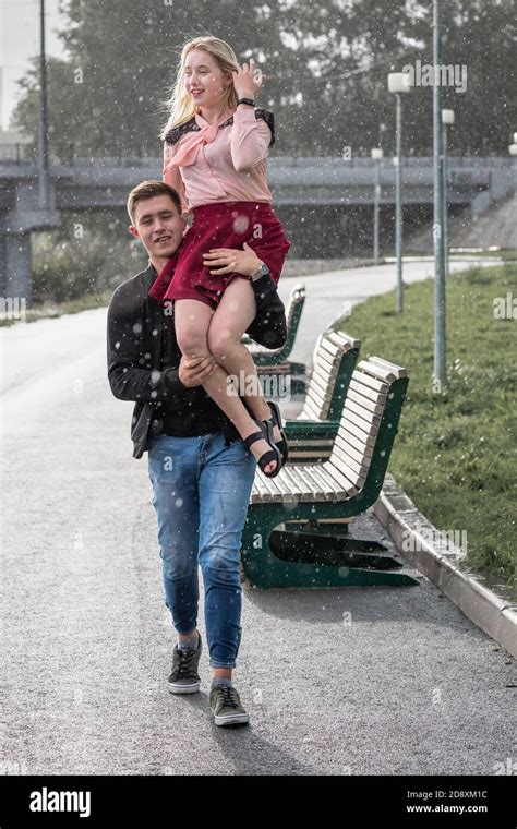 Strong Man Carrying His Woman On Shoulder In The Street On Rain Stock