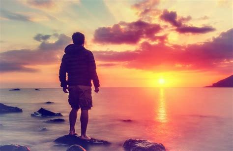Young Man Watching The Sunrise At Rocky Beach Free Stock Photo By