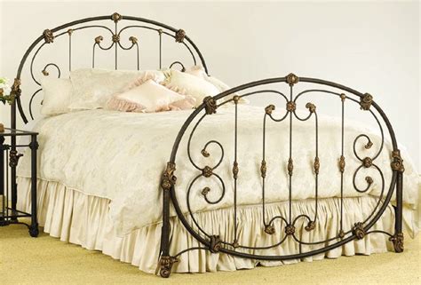 An Iron Bed Frame With White Sheets And Pink Pillows On Top Of The